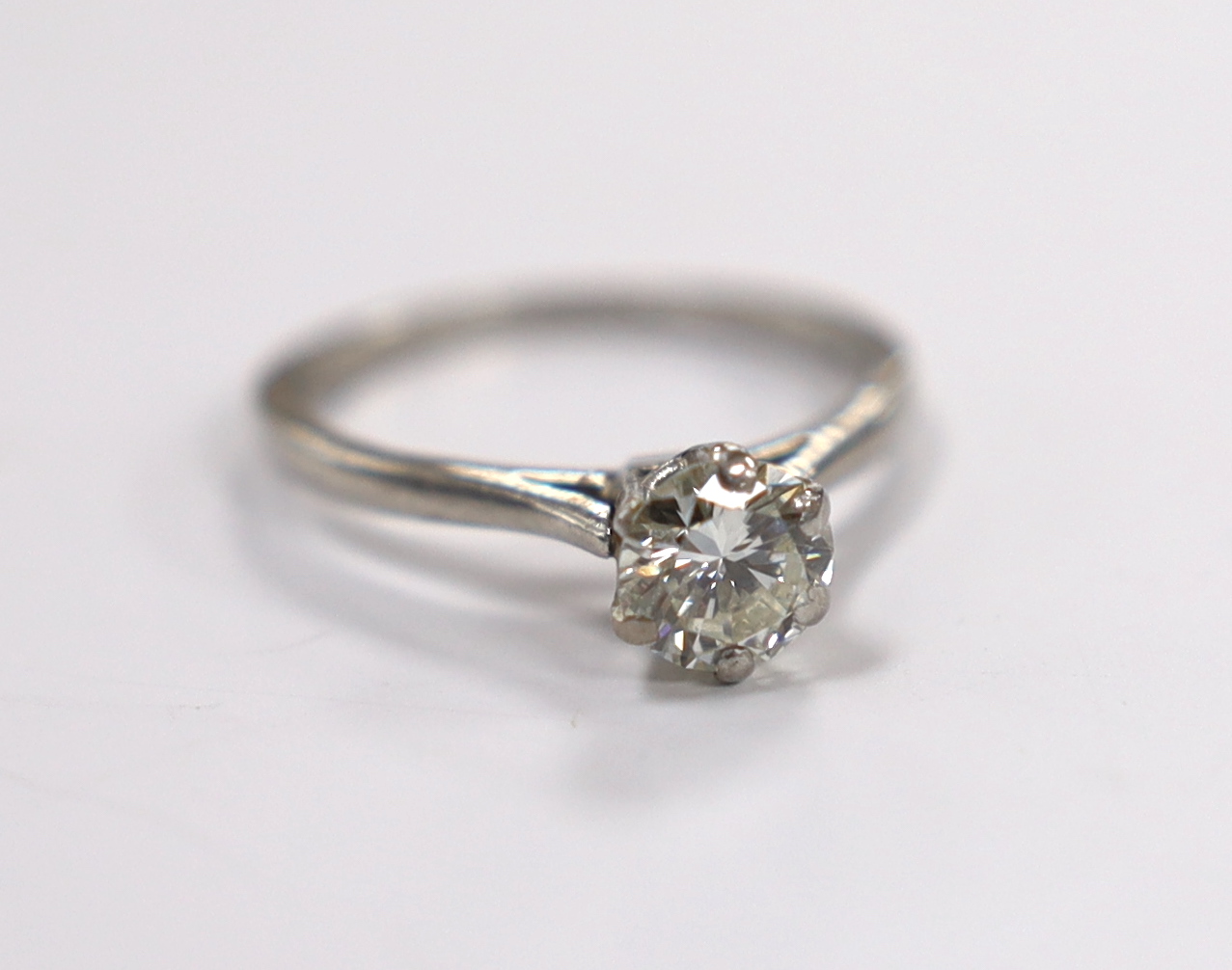 A white metal (stamped plat) and solitaire diamond set ring, size L/M, gross weight 3.5 grams, the stone with a diameter of 6mm.